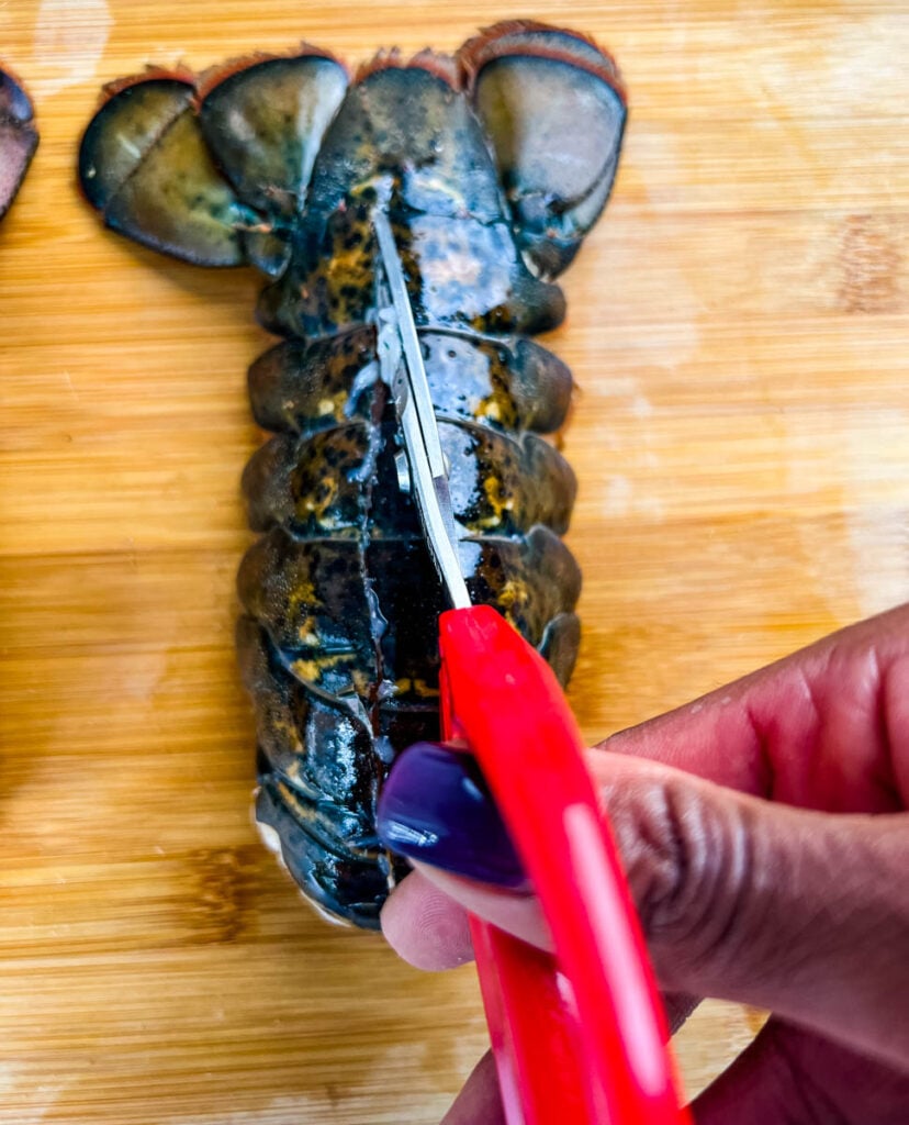 person slicing through lobster tail