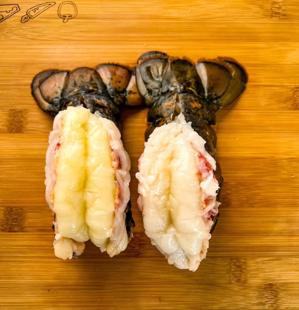 butterflied lobster tails on a wooden cutting board