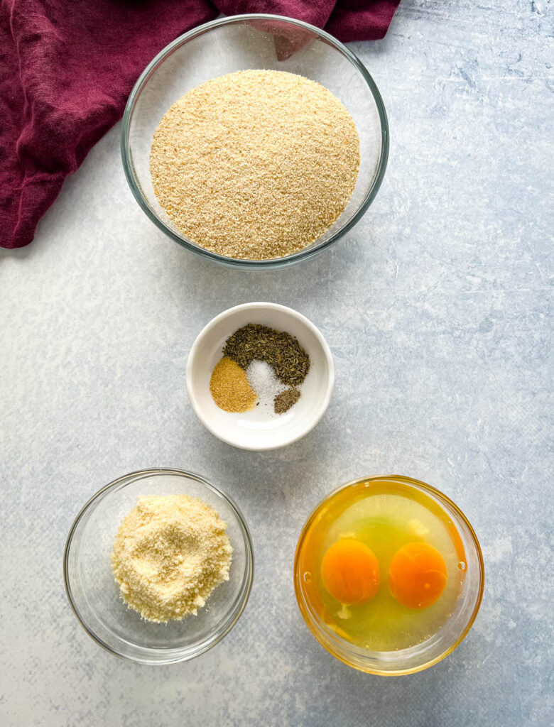 breadcrumbs, spices, grated parmesan cheese, and raw eggs in separate bowls