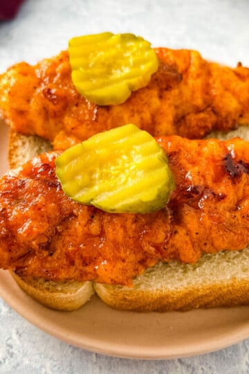Nashville hot chicken tenders on bread with pickles