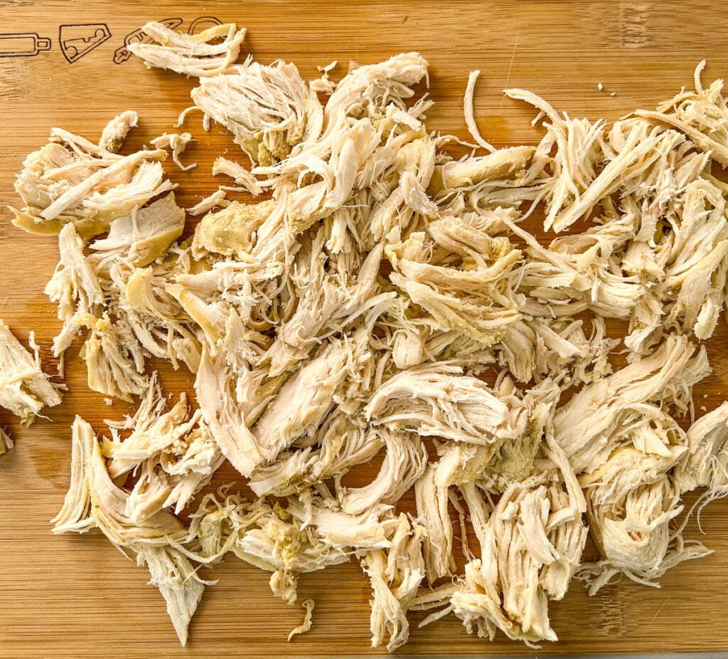 shredded chicken breasts on a wooden cutting board