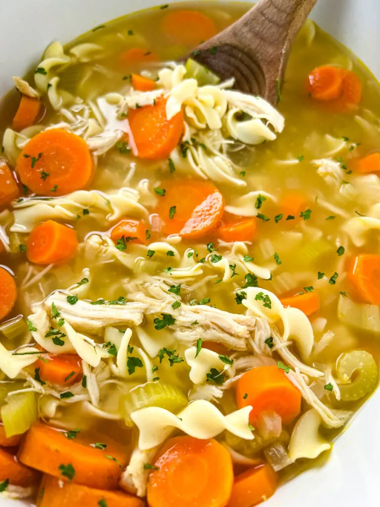 homestyle chicken noodle soup with carrots and vegetables in a pot