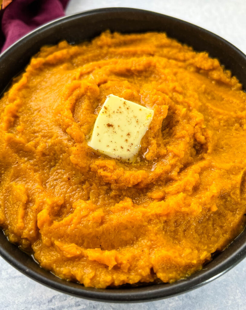 mashed sweet potatoes in a bowl with butter and brown sugar