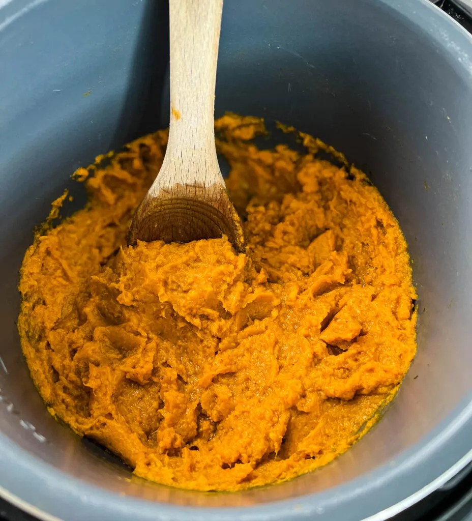 mashed sweet potatoes in a pot with a wooden spoon