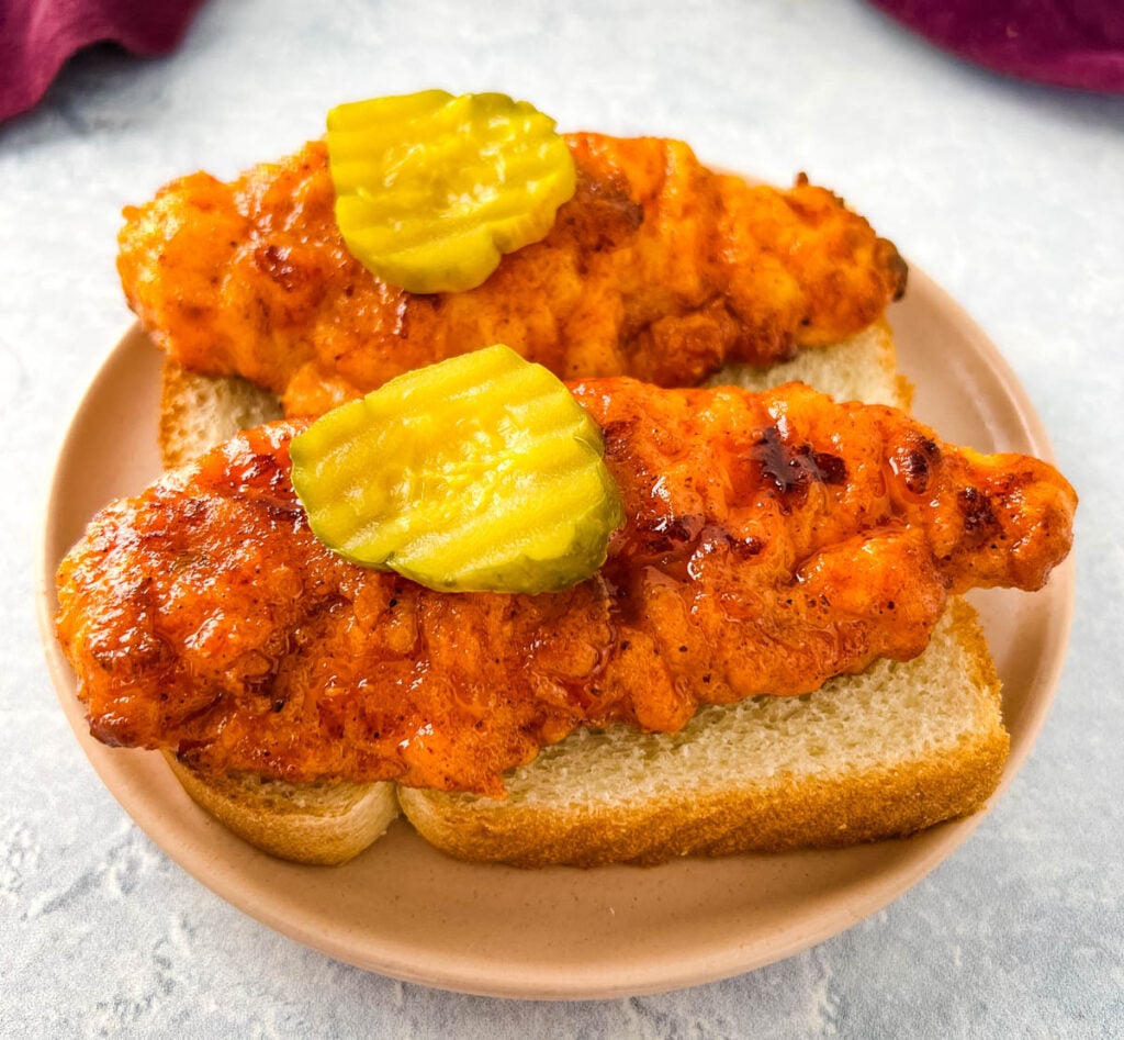 Nashville hot chicken tenders on bread with pickles