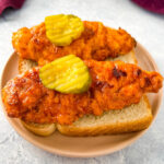 Nashville hot chicken tenders on bread with pickles