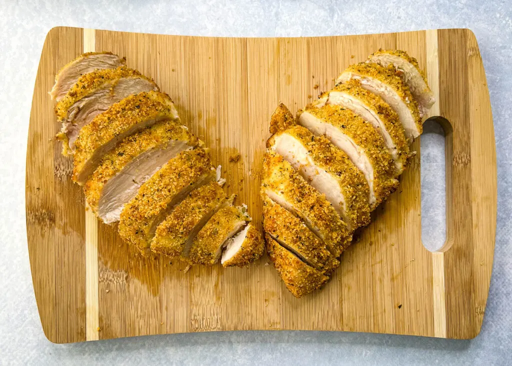 parmesan breaded chicken sliced on a cutting board