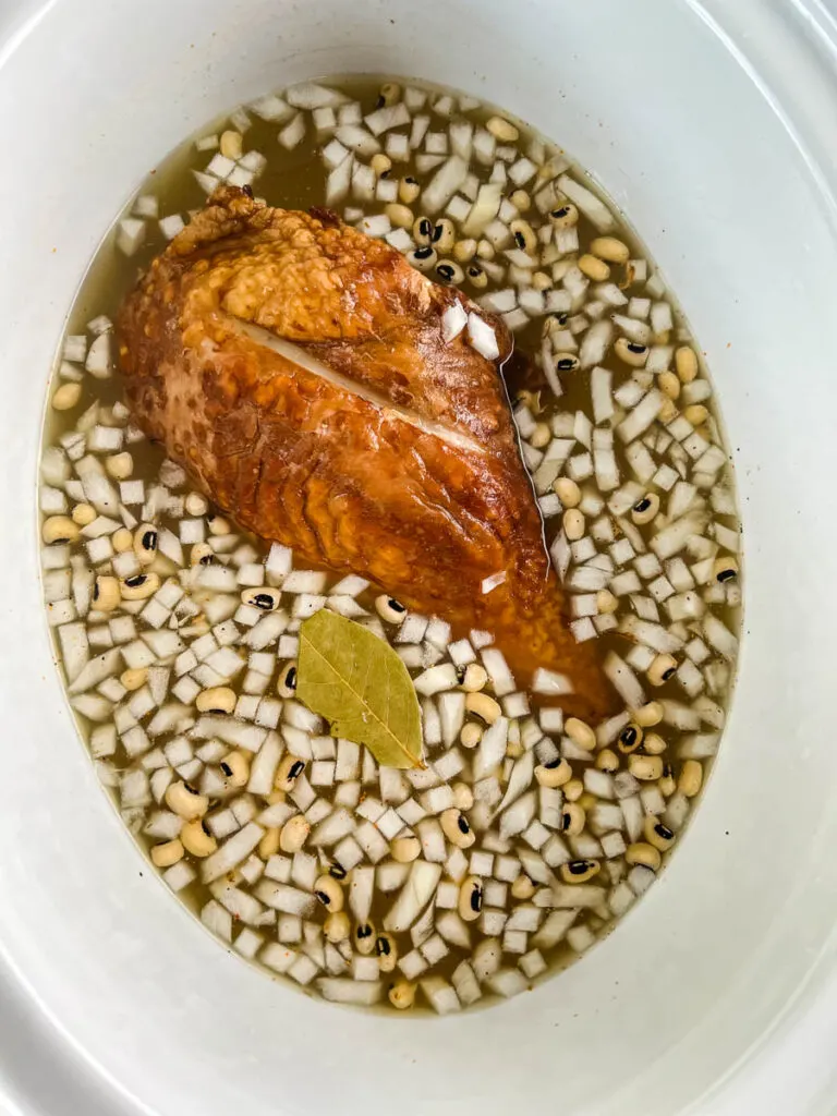 dried black eyed peas, onions, bay leaf, spices, and smoked turkey, and broth in slow cooker Crockpot