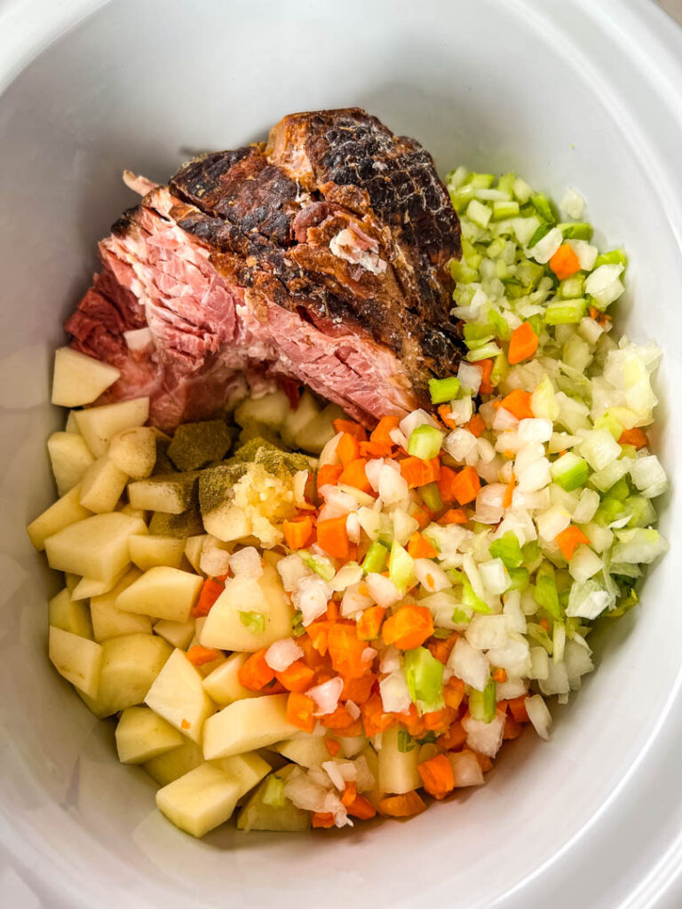 uncooked slow cooker ham and potato soup in a Crockpot with vegetables