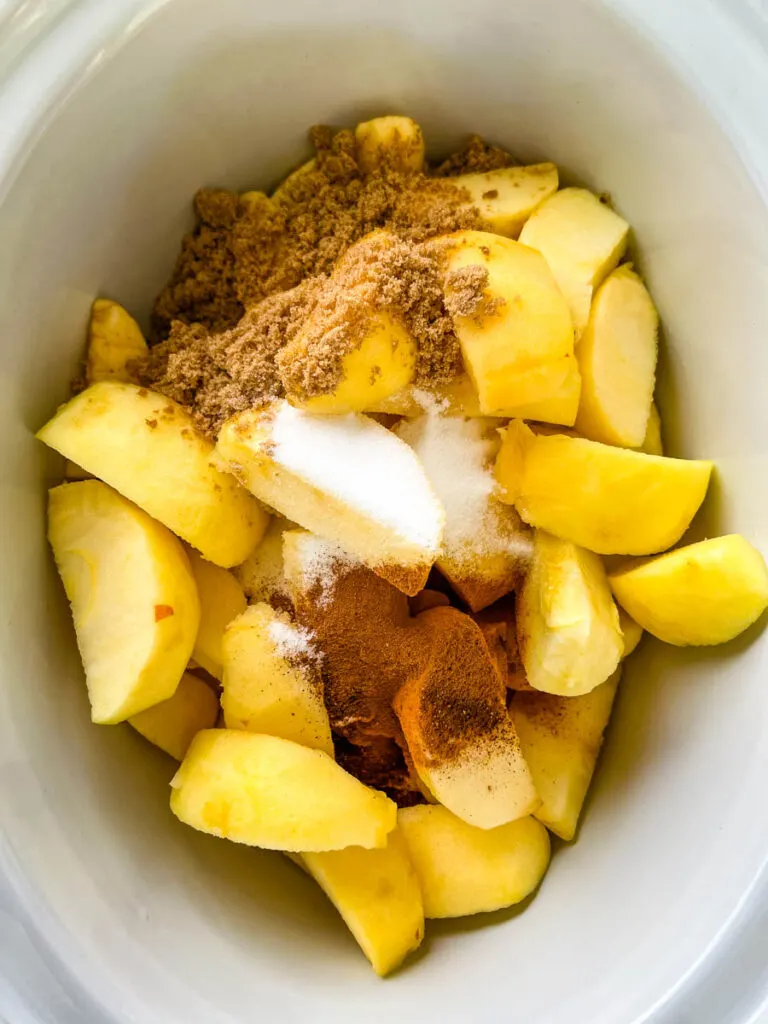 sliced apples in a slow cooker with spices and sweetener