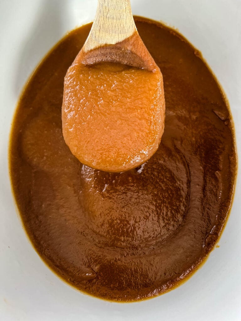sugar free apple butter in a slow cooker with a wooden spoon