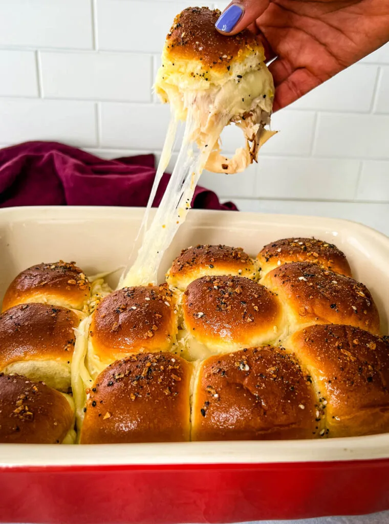 person holding turkey cheese slider with melted cheese