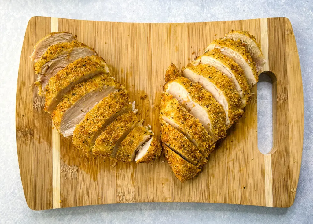 air fryer parmesan crusted chicken sliced on a bamboo cutting board