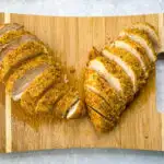 air fryer parmesan crusted chicken sliced on a bamboo cutting board