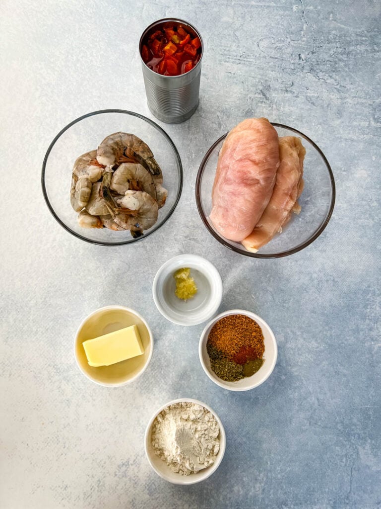 raw chicken breasts, raw shrimp, diced tomatoes, butter, flour, and spices in separate bowls