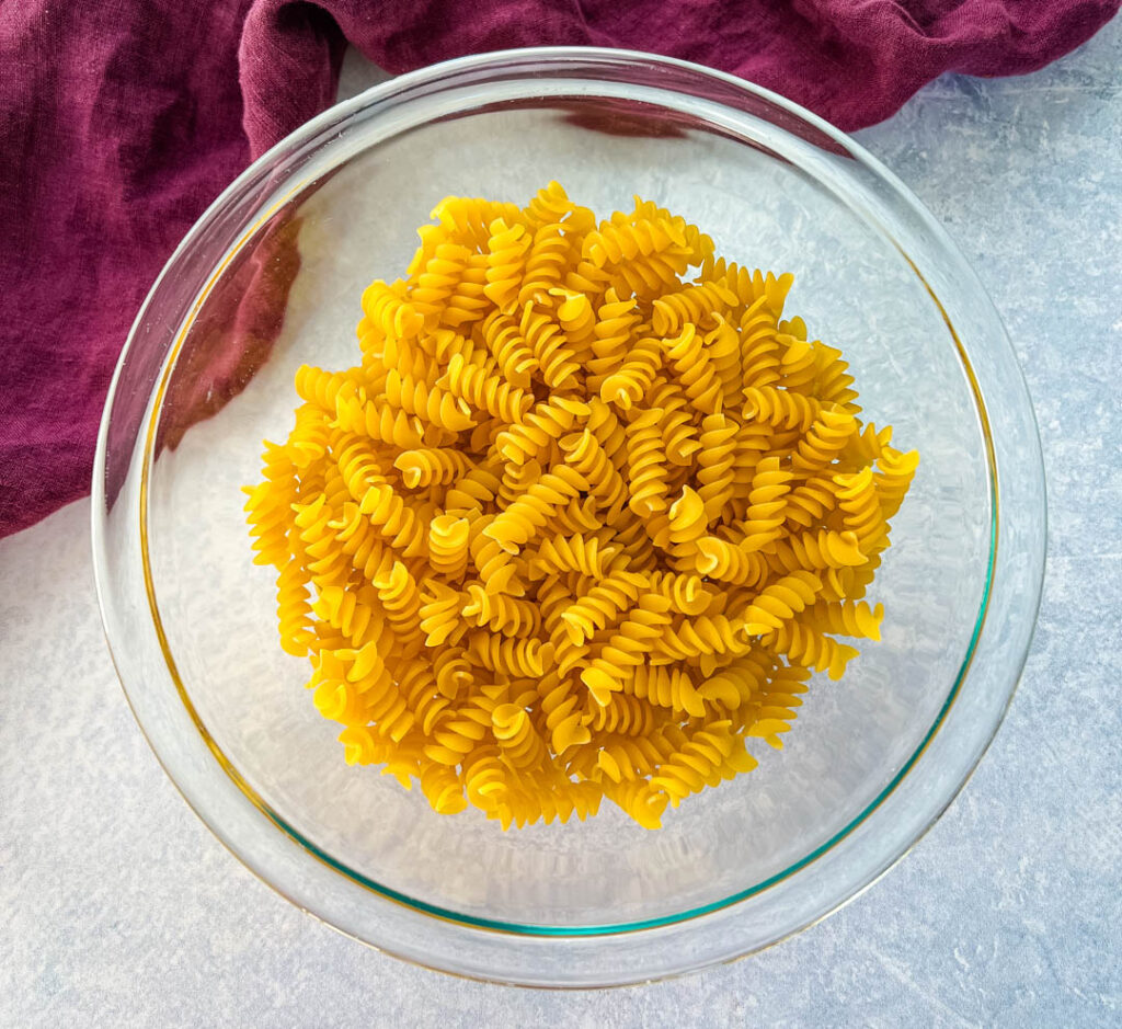 uncooked rotini pasta in a glass bowl
