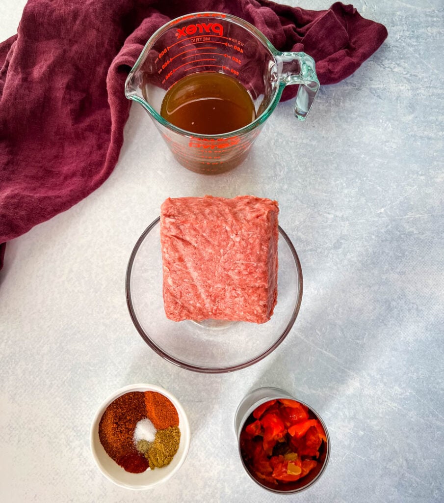 raw ground beef, beef broth, spiced, and diced tomatoes in separate bowls