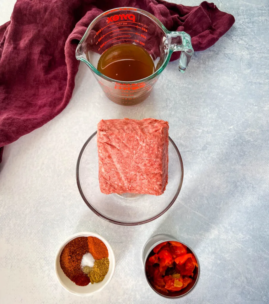 raw ground beef, beef broth, spiced, and diced tomatoes in separate bowls