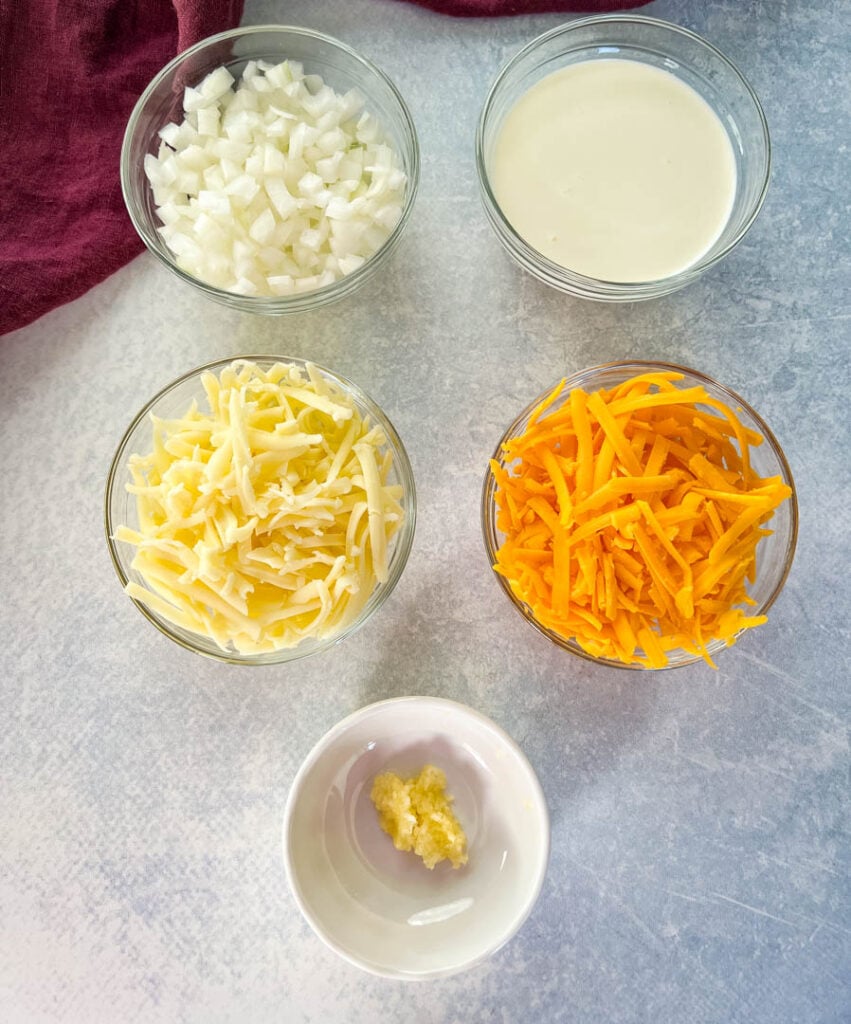 chopped onions, heavy cream, shredded cheese, and minced garlic in separate bowls