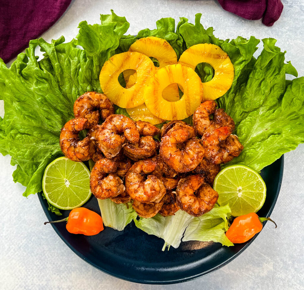 jerk shrimp on lettuce with pineapples, limes, and fresh peppers