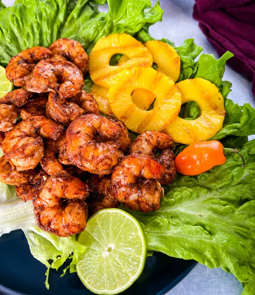 jerk shrimp on lettuce with pineapples, limes, and fresh peppers