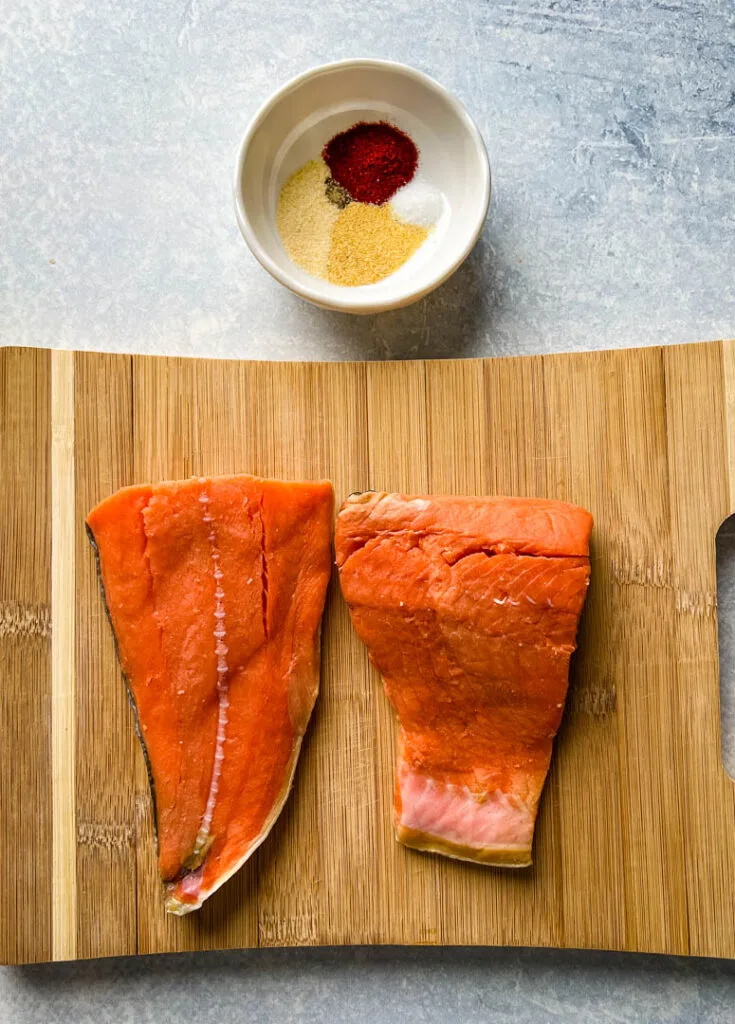 raw salmon on a cutting board with spices