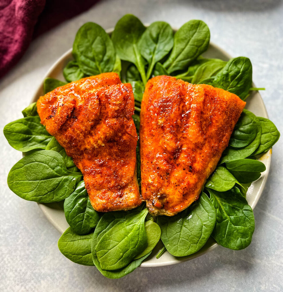 cooked indoor grilled salmon on a plate with fresh spinach