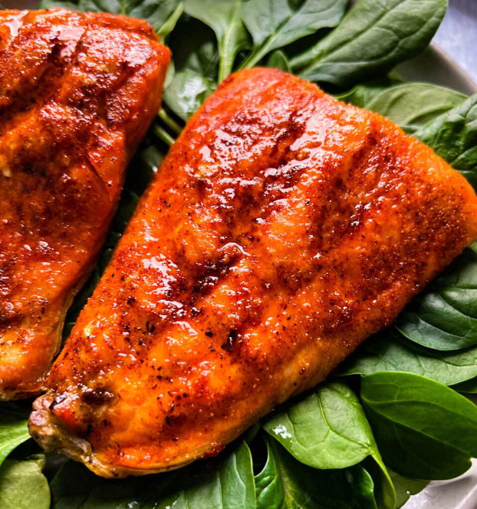 cooked indoor grilled salmon on a plate with fresh spinach