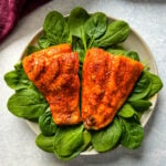cooked indoor grilled salmon on a plate with fresh spinach