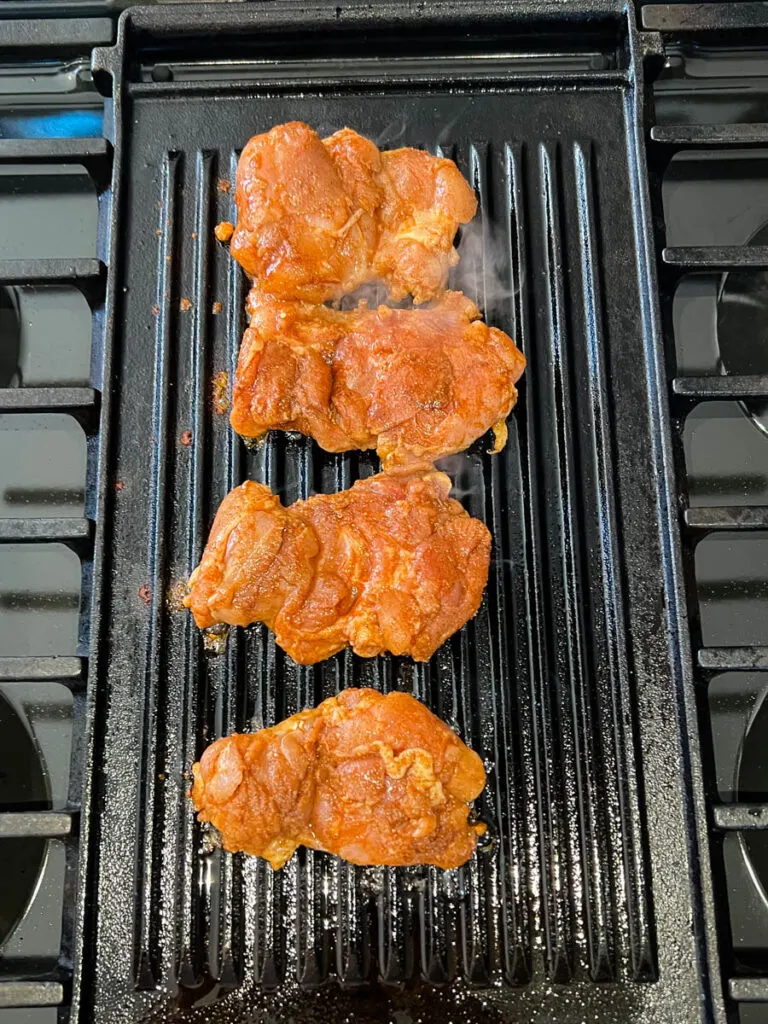 uncooked jerk chicken thighs on a grill pan