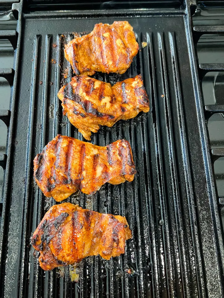 cooked jerk chicken thighs on a grill pan