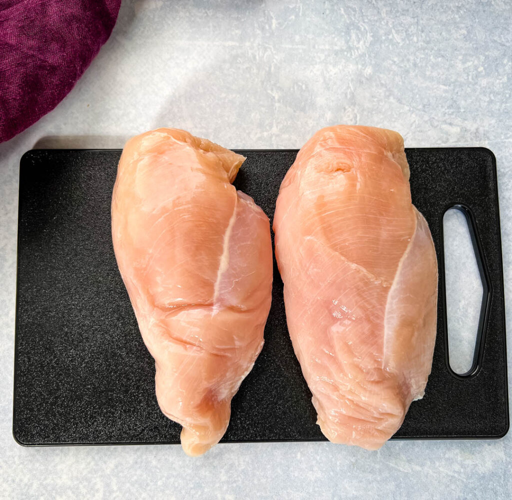 raw chicken breasts on a cutting board