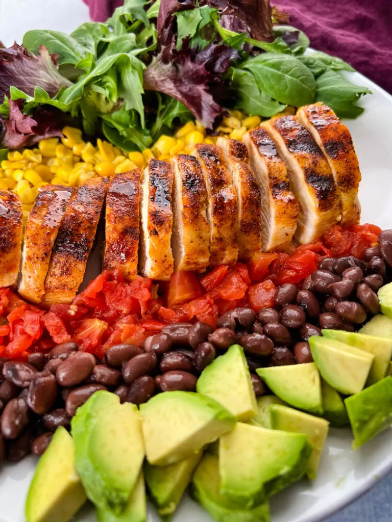 southwest salad with lettuce, corn, chicken, tomatoes, black beans, and avocado on a plate