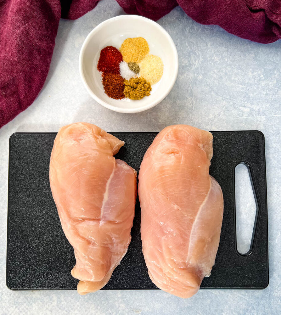 raw chicken breasts and spices on a flat surface