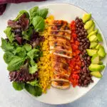 southwest salad with lettuce, corn, chicken, tomatoes, black beans, and avocado on a plate
