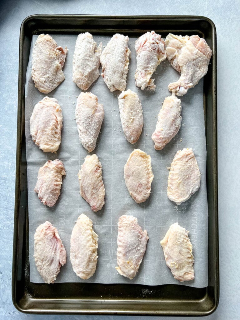 dry rub floured chicken wings on a sheet pan