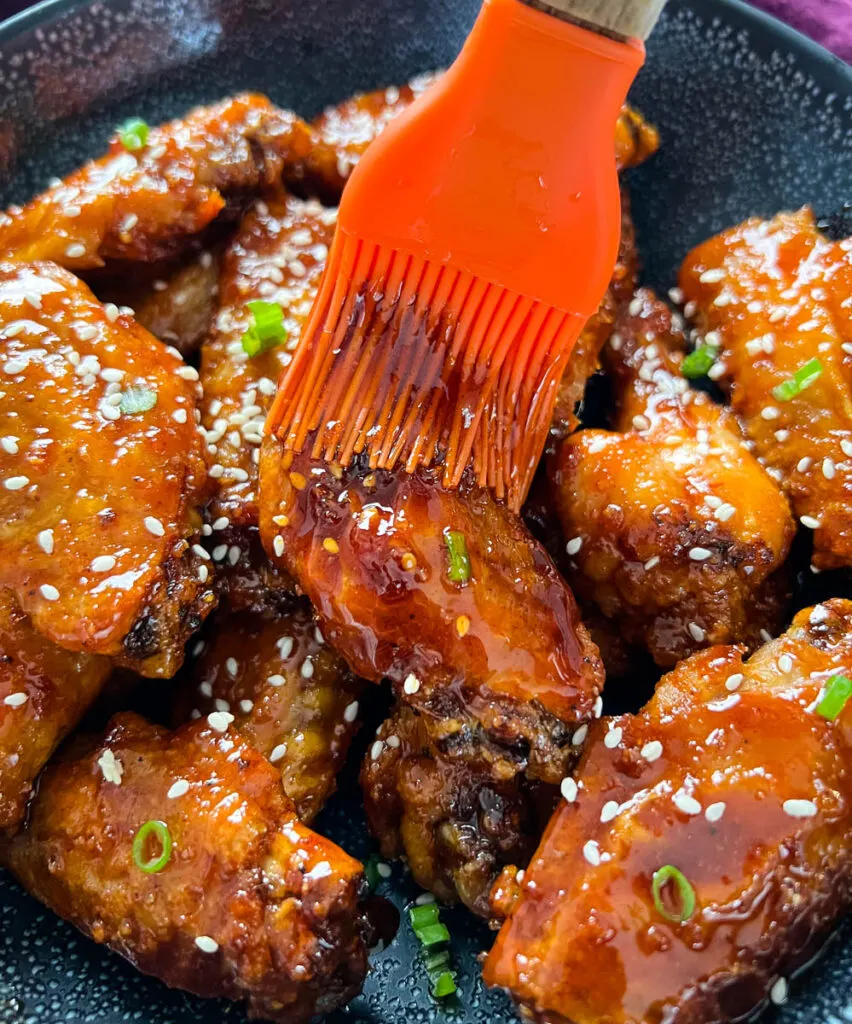honey garlic chicken wings drizzled with sauce with a cooking brush