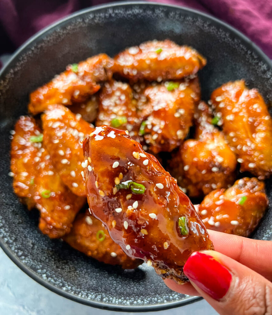 person holding honey garlic chicken wing