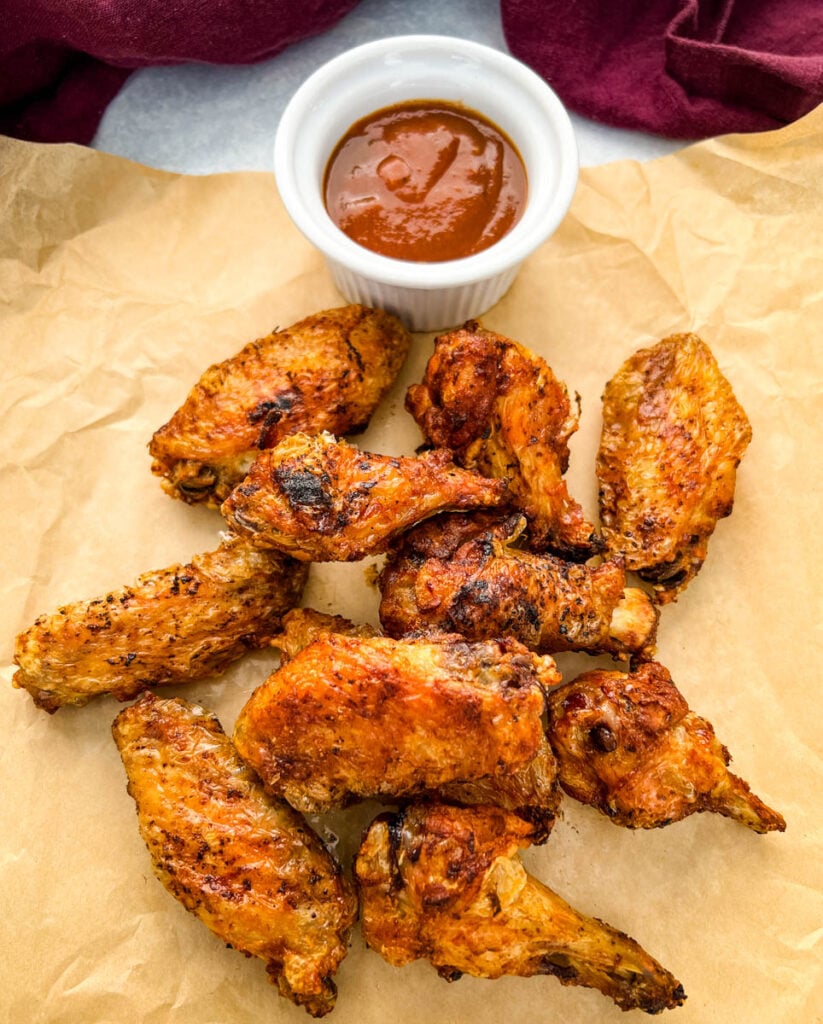 cooked chicken wings on brown paper with BBQ sauce