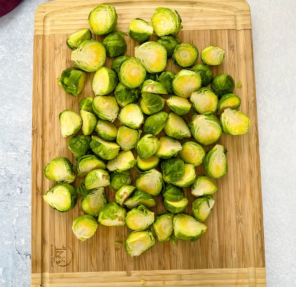 raw halved brussels sprouts on a wooden cutting board