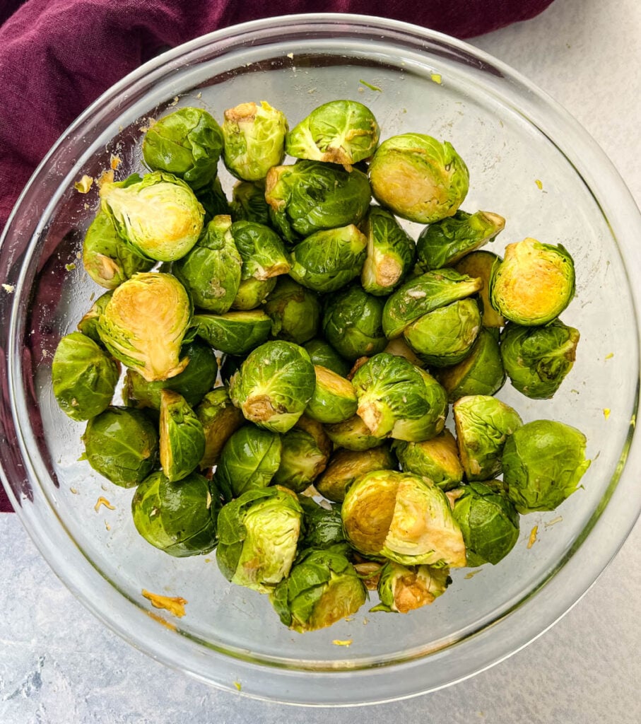 fresh, raw brussels sprouts in a glass bowl with garlic and balsamic vinegar