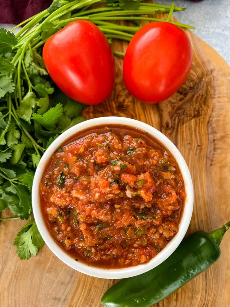 smoked salsa in a white bowl on a platter with fresh tomatoes, cilantro, and jalapeno