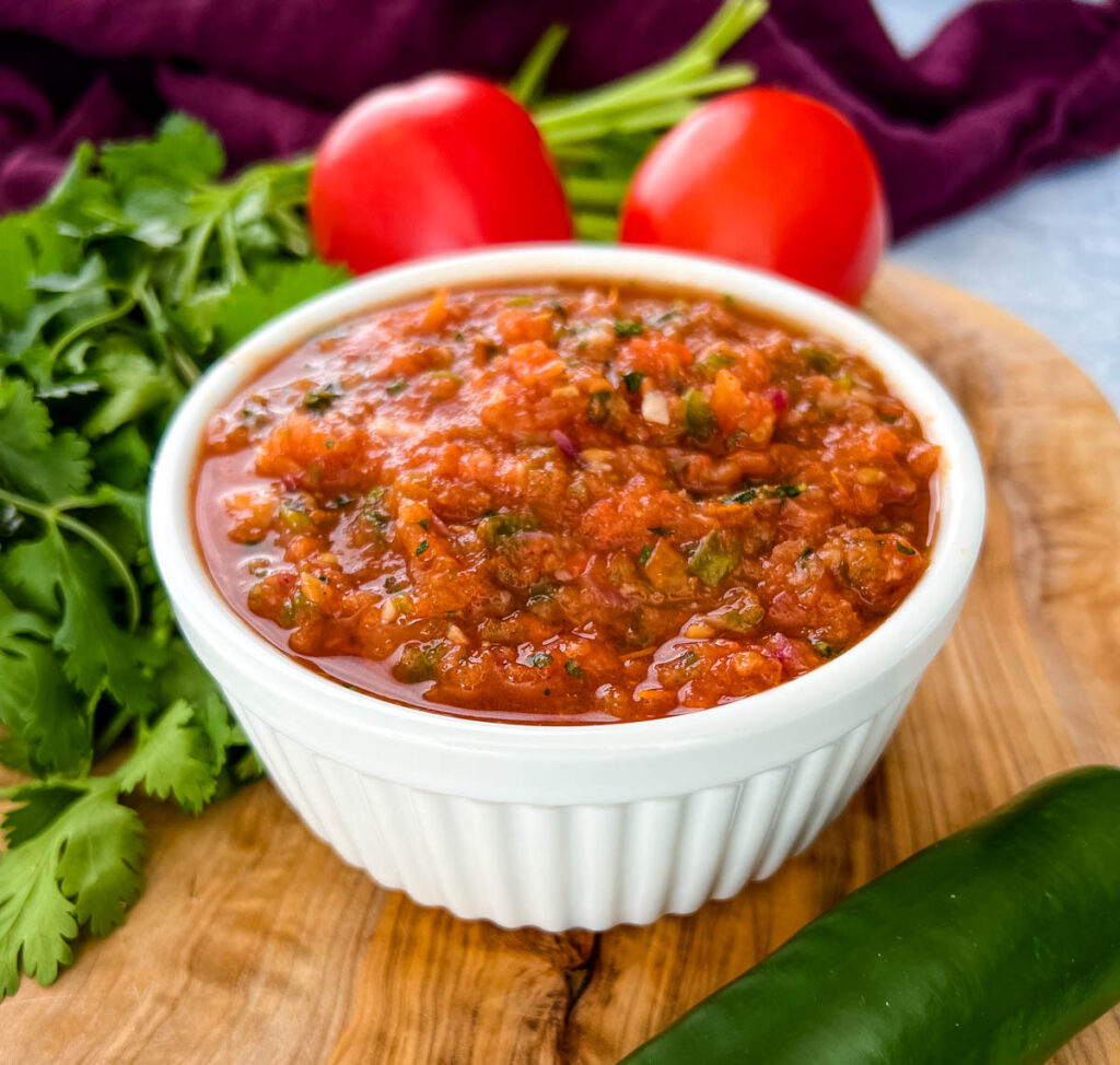 smoked salsa in a white bowl on a platter with fresh tomatoes, cilantro, and jalapeno