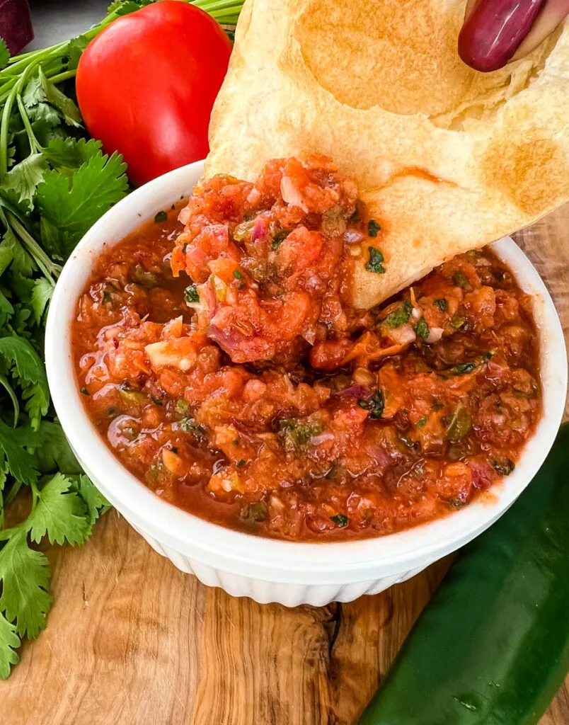 person holding a chip with smoked salsa