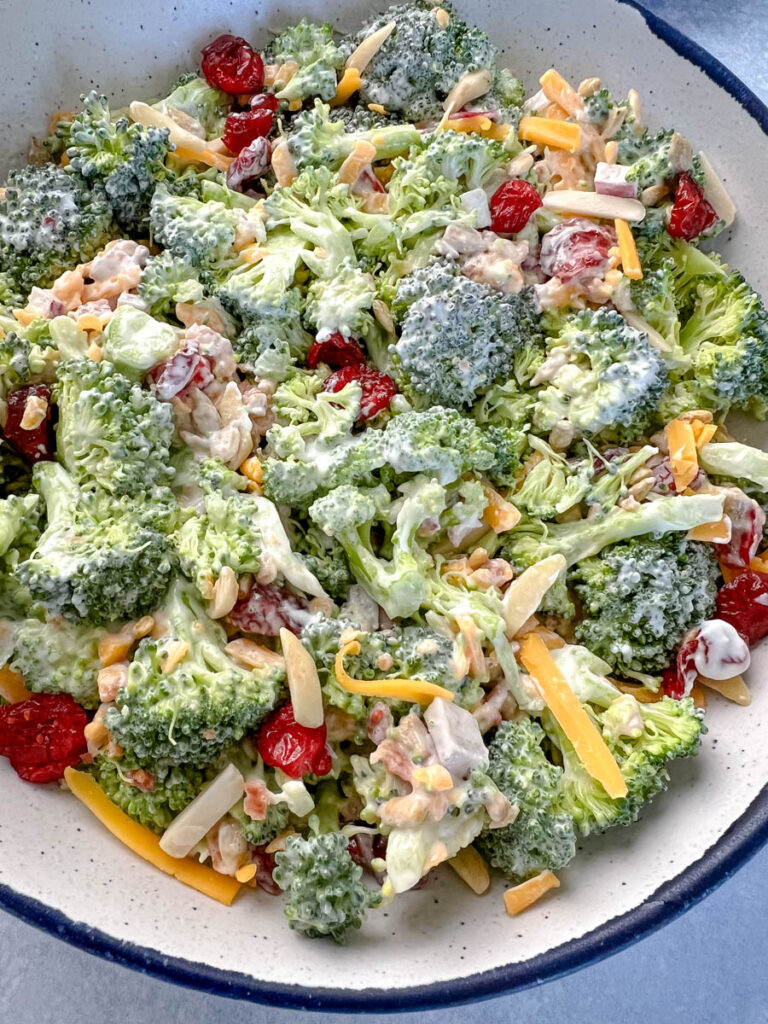 broccoli salad with cheese, bacon, and cranberries in a white bowl