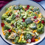 broccoli salad with cheese, bacon, and cranberries in a white bowl