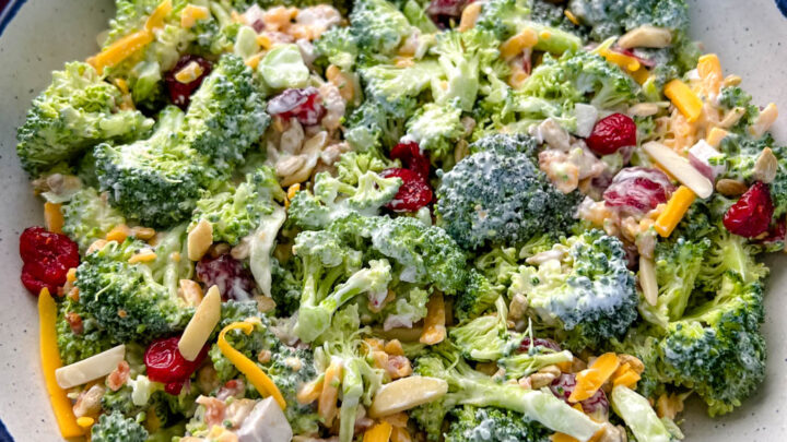 broccoli salad with cheese, bacon, and cranberries in a white bowl