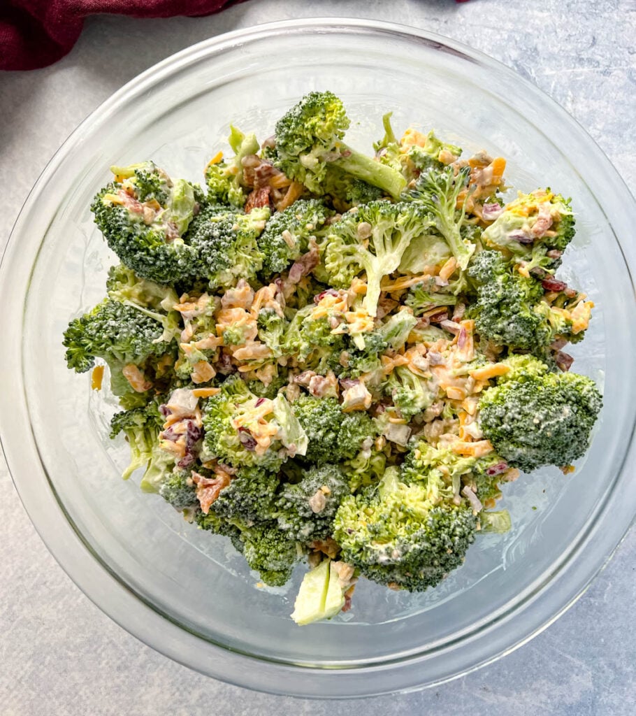 broccoli salad with cheese, bacon, and cranberries in a glass bowl