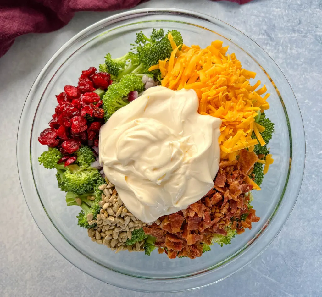 broccoli salad with cheese, bacon, and cranberries in a glass bowl