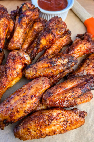 Traeger smoked chicken wings on a plate with BBQ sauce